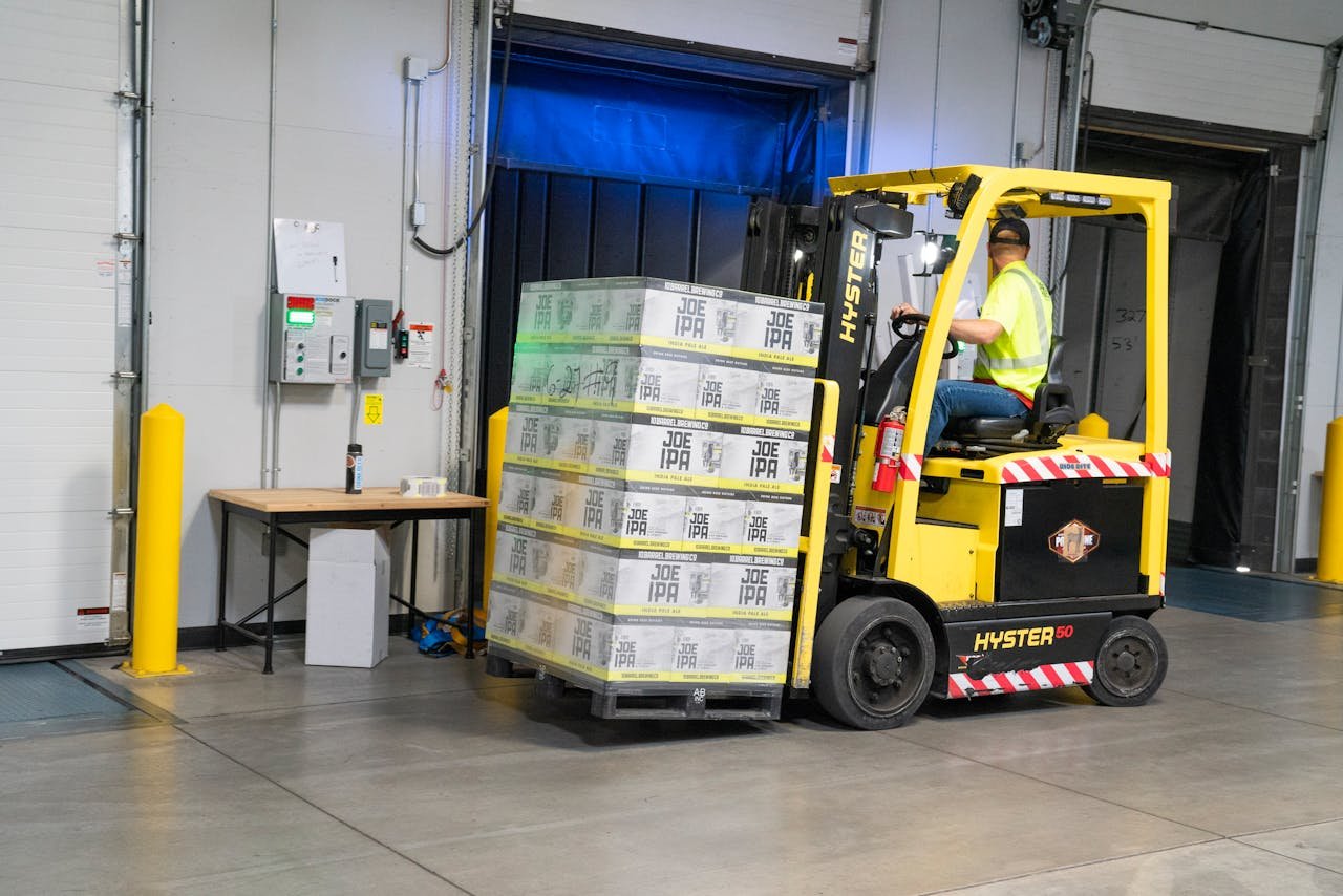 Home A warehouse employee operating a forklift to move stocked goods indoors. Perfect for industry and logistics visuals.
